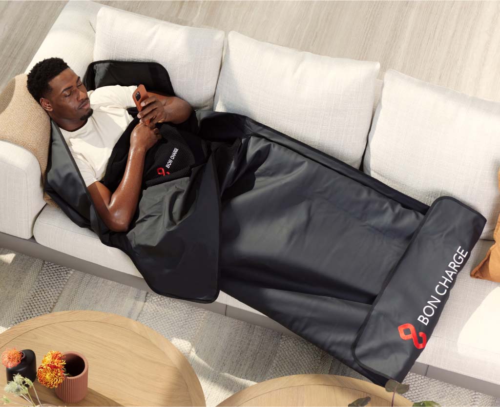 Man Laying On Sofa Relaxing Inside Sauna Blanket